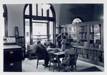 "Art collection. Librarian at bookshelf with girl, others reading [58th Street Branch]" The New York Public Library Digital Collections. 1875.