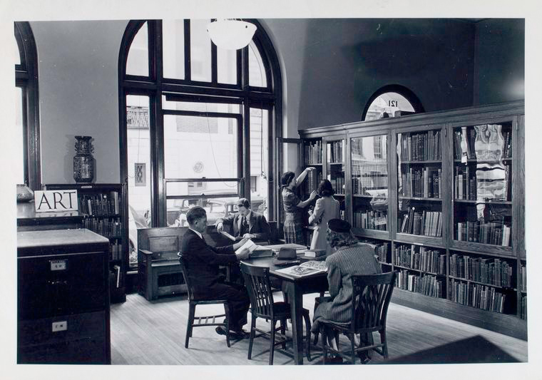 Librarian at bookshelf with girl, others reading [58th Street Branch]